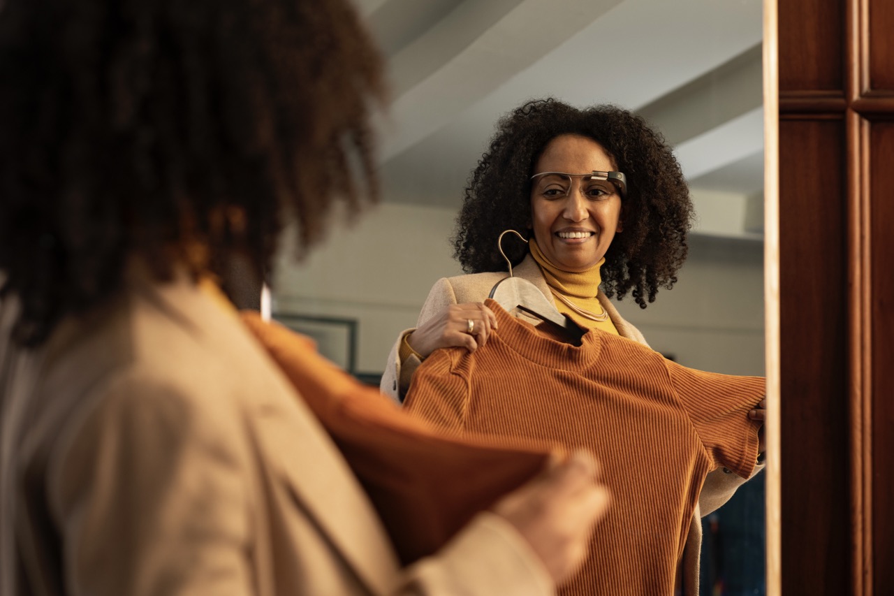 Image of woman using the Envision Glasses, wearables for low vision and blindness, to video call a friend to help her chose a sweater to wear