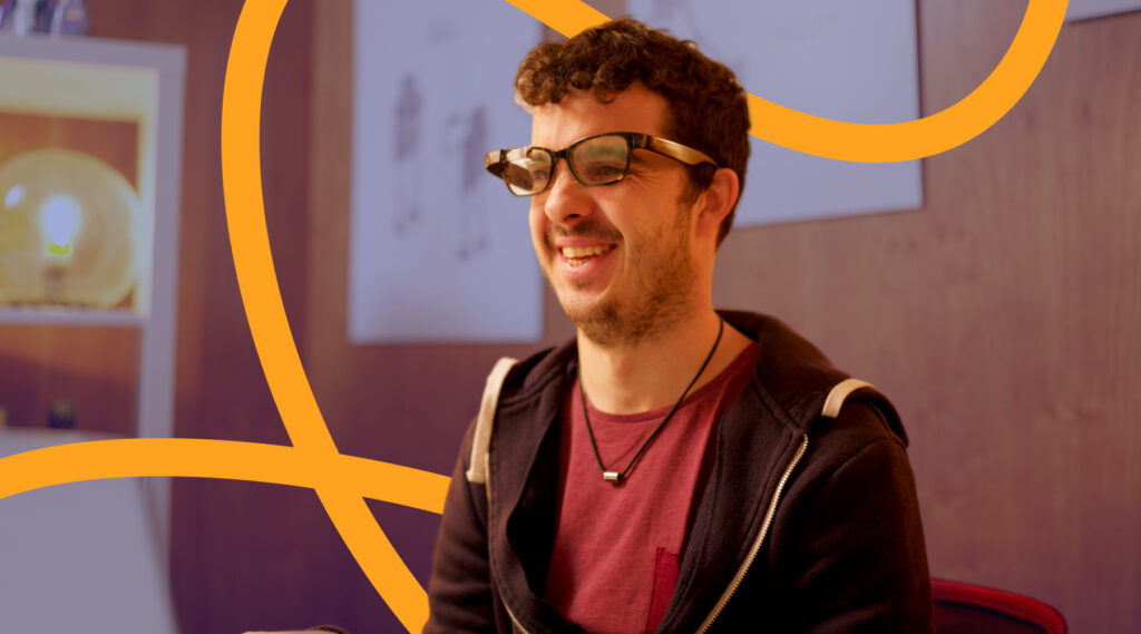 a man sitting down smiling wearing his envision glasses while speaking with ally