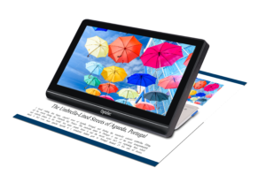 Image of the compact 8 video magnifier sitting on a flyer showing a magnified image of umbrellas