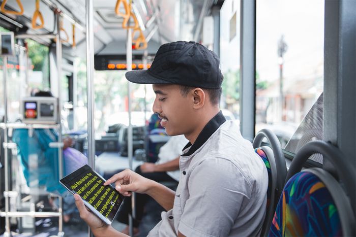 Image of the Connect 12- Smart Portable HD Magnifier being used by an individual riding in a bus who is reading an e-book