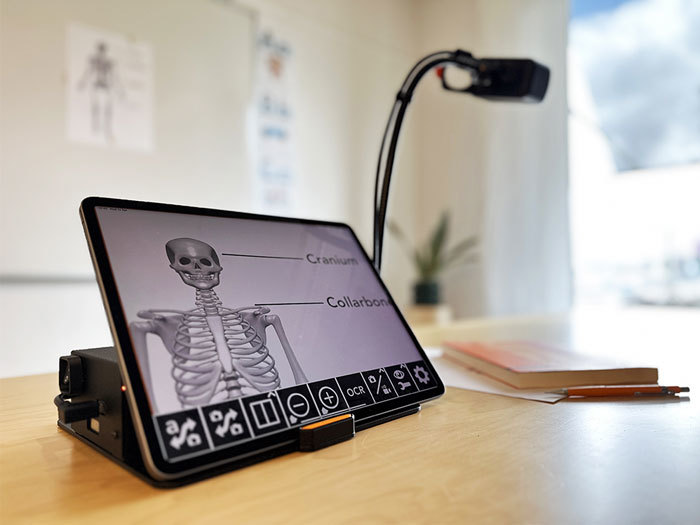 Image of the MagniLink WifiCam attached to a tablet being used at school to view a document of the human Skelton. 