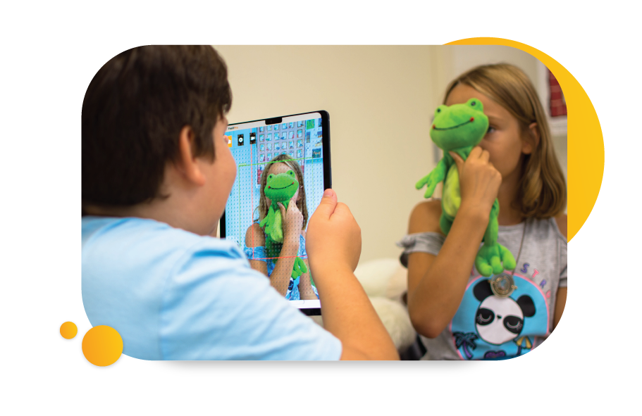 Image of child using the  to take a photo of his friend holding up a toy frog