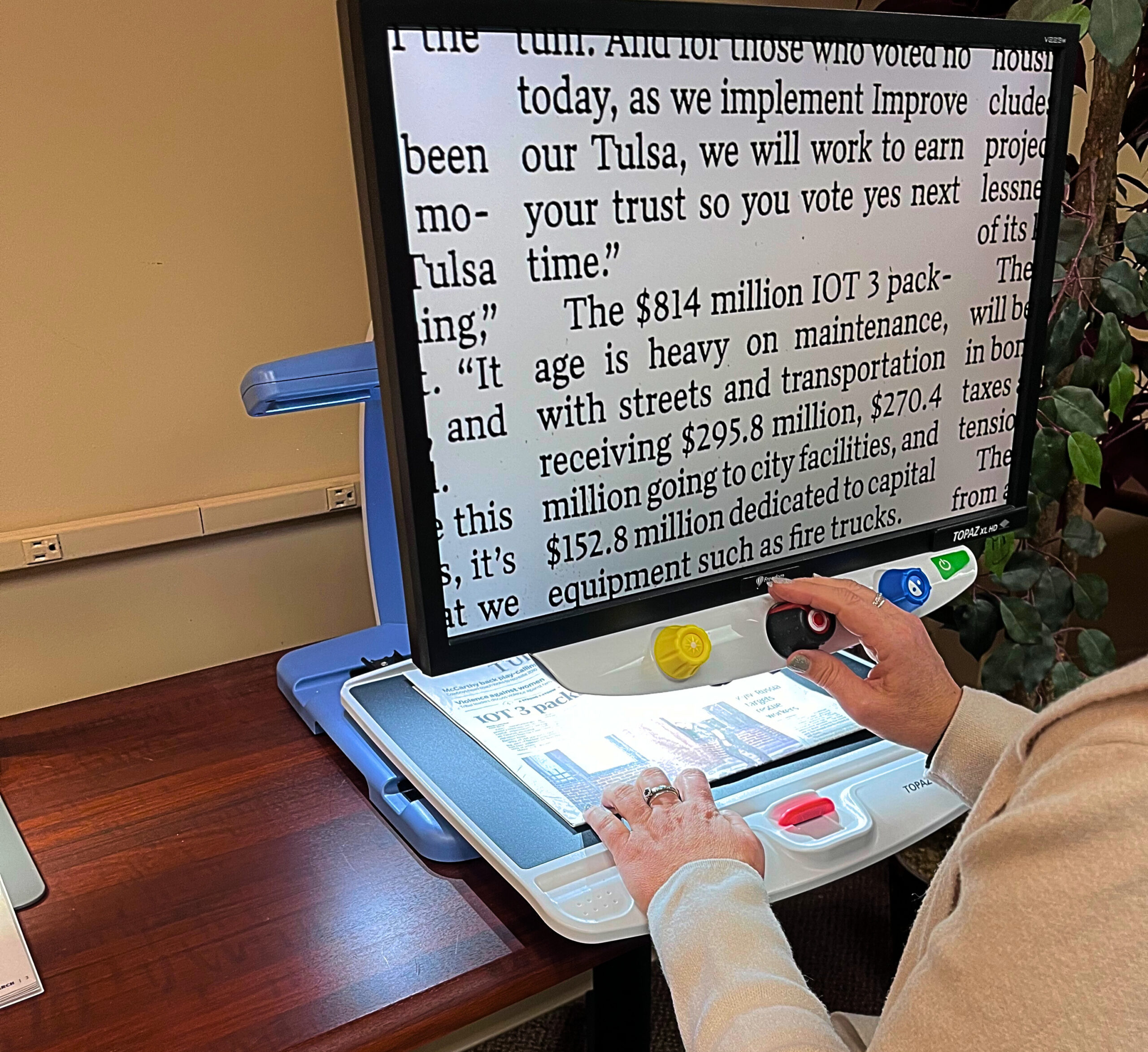 Image of maria from NanoPac reading the newspaper on a Topaz Desktop Video Magnifier in the NanoPac Demonstration Room in Tulsa 