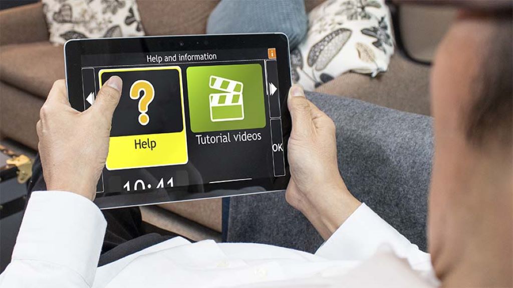 Image of a man hold a tablet with GuideConnect installed viewing the "Help and Information" page of the software.